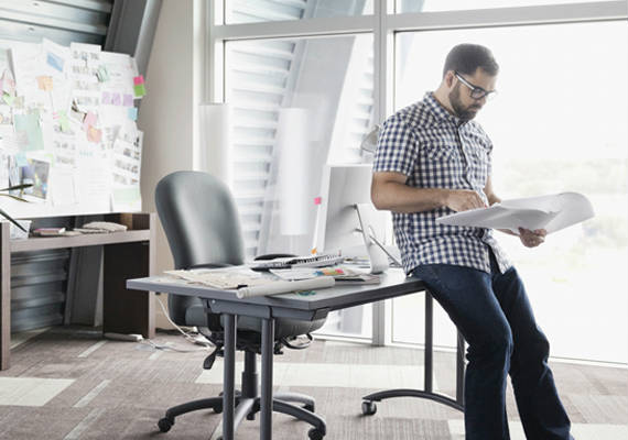 Man sitting at a desk with a whiteboard looking over a report
